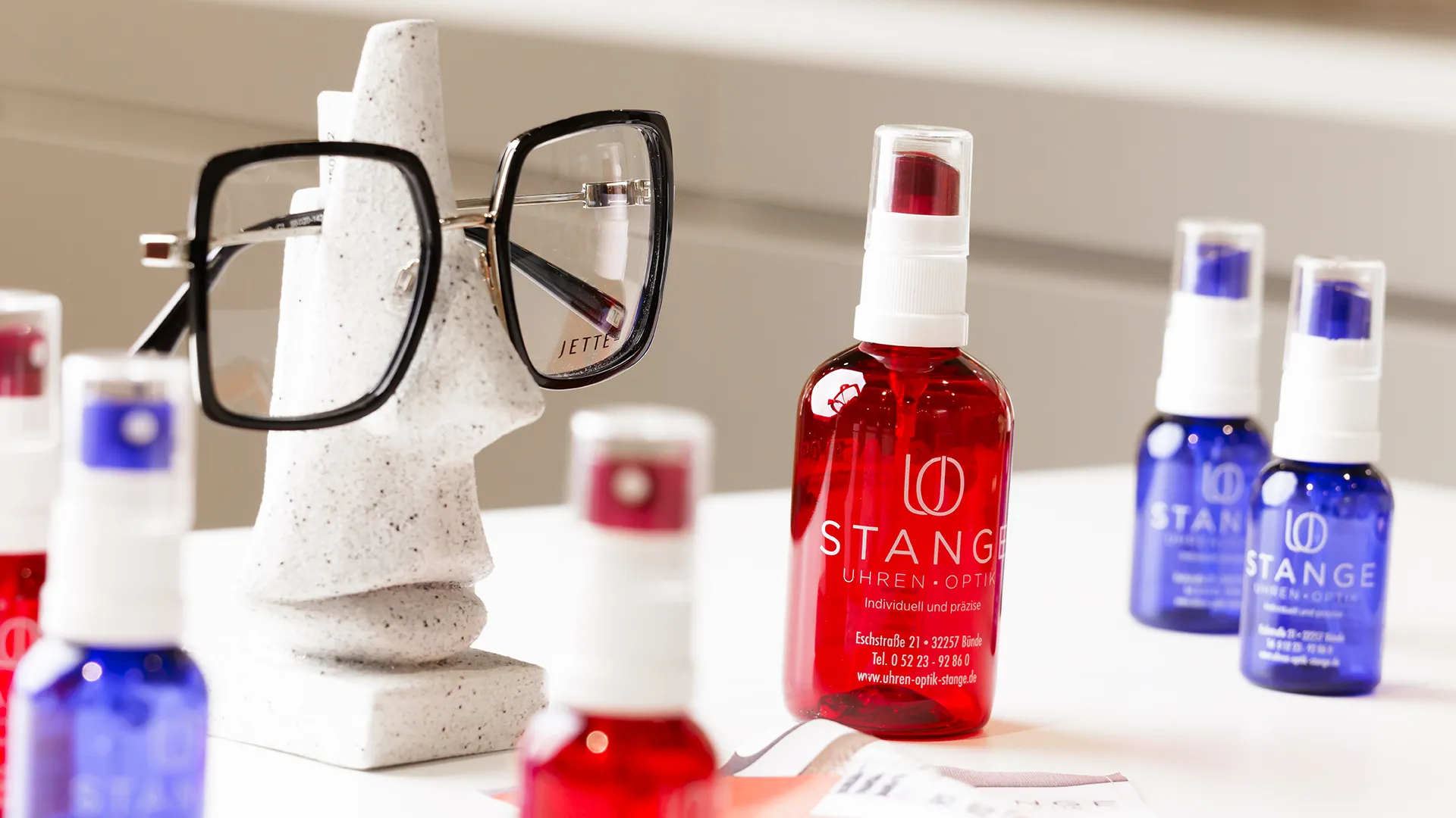 Brillenreinigungssprays von STANGE und eine Brillenfassung auf Deko-Nasenständer bei Uhren Optik Arnold Stange in Bünde