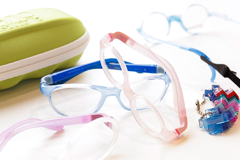 Kinderbrillen von NANO Vista mit Wechselbügeln, Sportband und grünem Etui auf weißem Tisch